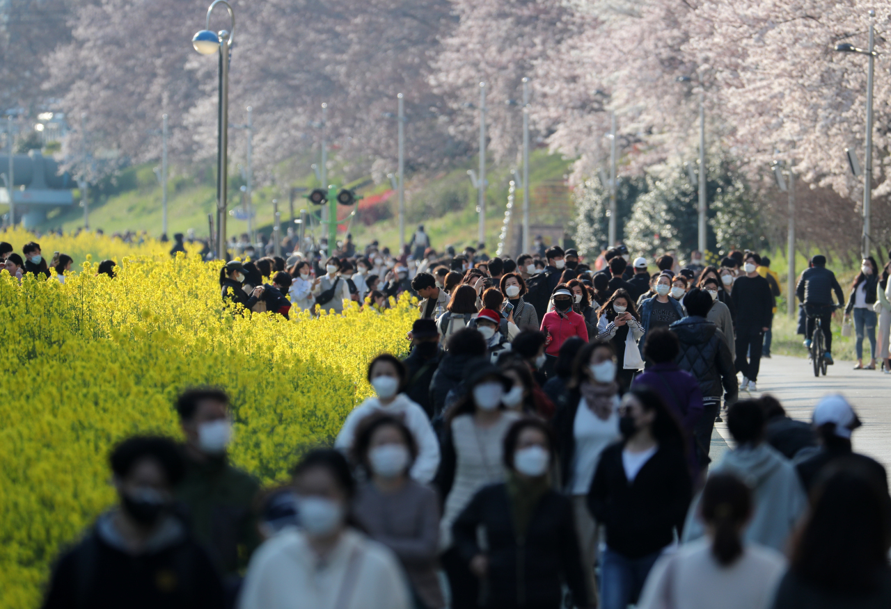 Peole taking a walk at a public park in Busan enjoying rape flowers and cherry blossoms. Yonhap