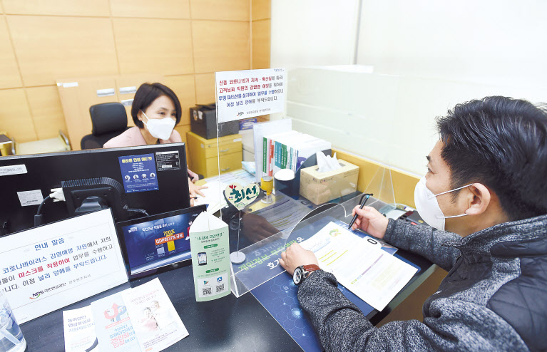 국민연금공단이 코로나19 극복에 전사적으로 대응하고 있는 가운데 전주완주지사에서 직원이 마스크를 쓴 채 투명 칸막이(파티션)이 설치된 창구에서 고객상담 업무를 수행하고 있다. [국민연금공단 제공]