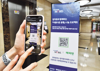 현대모비스 직원이 모바일 QR코드 방식으로 자발적 기부 캠페인에 참여하고 있다. [현대모비스 제공]
