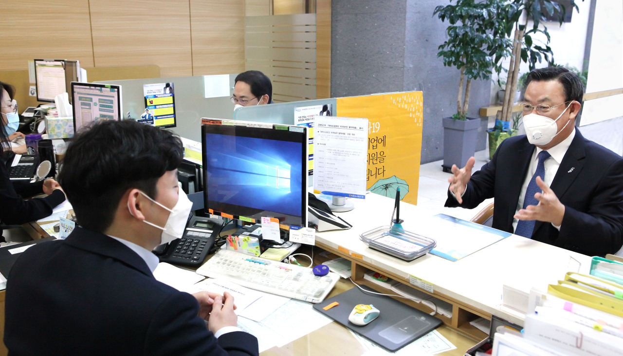 Korea Federation of Banks Chairman Kim Tae-young discusses the topic of extending loans to small businesses with a NH Nonghyup Bank employee in central Seoul on April 2. (Yonhap)