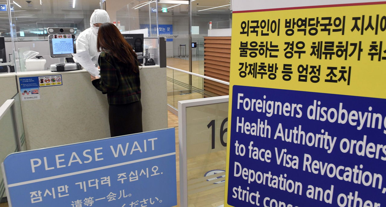 전신 방호복을 입은 인천국제공항 출입국 외국인청 입국심사관이 8일 오후 유증상자 전용 입국심사대에서 입국심사 후 자가격리 지침을 설명하고 있다. [연합]