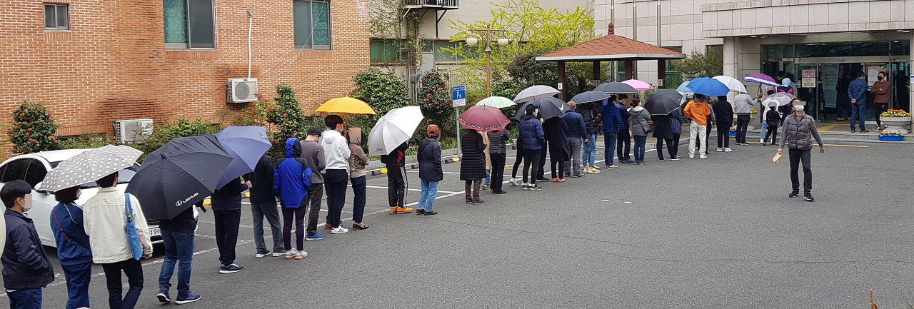 11일 오후 울산시 남구 옥동 울산보훈지청 사전투표소에서 줄을 길게 늘어선 유권자들이 갑작스럽게 비가 내리자 우산을 꺼내 쓰거나 그대로 비를 맞으면서 투표 순서를 기다리고 있다. [연합뉴스]