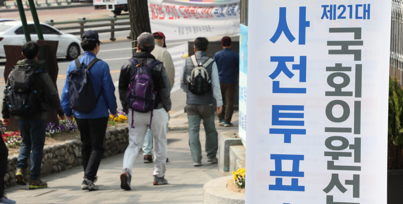 21대 국회의원 사전투표 마지막 날인 11일 주말 등산객들이 종로구 사전투표소 안내판 옆을 지나고 있다. 이번 총선 사전투표율은 26.69%로 역대 최고를 기록했다. [연합]
