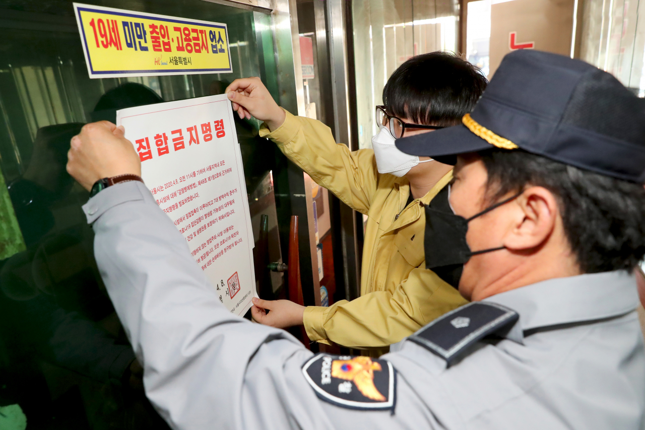 지난 9일 성동구 보건소 관계자와 경찰이 서울 성동구의 한 유흥업소에 집합금지 명령서를 붙이고 있다. [성동구 제공]