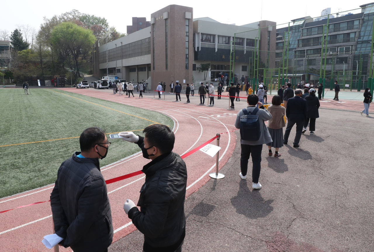 A poll worker takes temperature from a voter at a polling station in Dongjak, a southern Seoul district. (Yonhap)