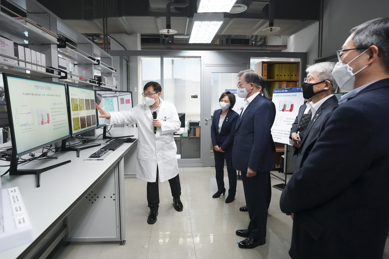 문재인 대통령이 9일 오전 경기 성남시 한국파스퇴르연구소 연구 시설에서 김승택 연구팀장에게 코로나19 대응 약물 재창출 과정 및 데이터 분석에 대한 설명을 듣고 있다. 연합뉴스