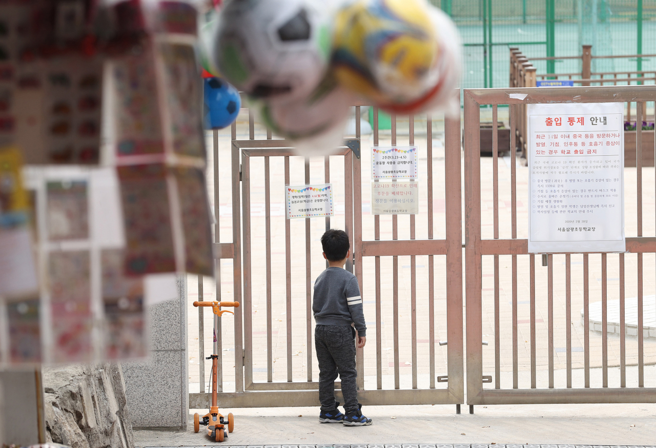 지난 달 31일 오후 서울 용산구 한 초등학교에서 한 어린이가 닫혀진 문을 바라보고 있다. [연합]
