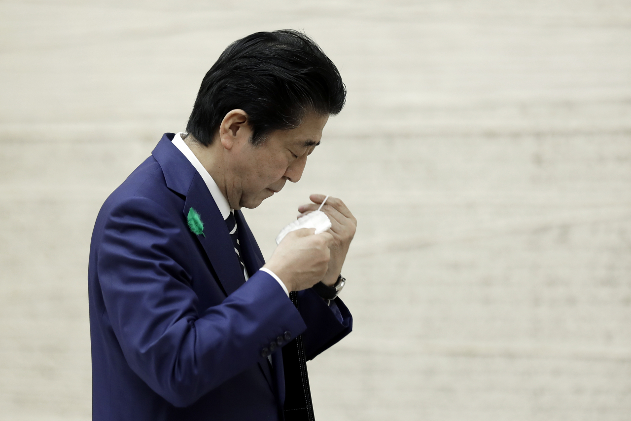 지난 17일 아베 신조 일본 총리가 기자회견을 마치고 마스크를 다시 쓰고 있다. [AP]