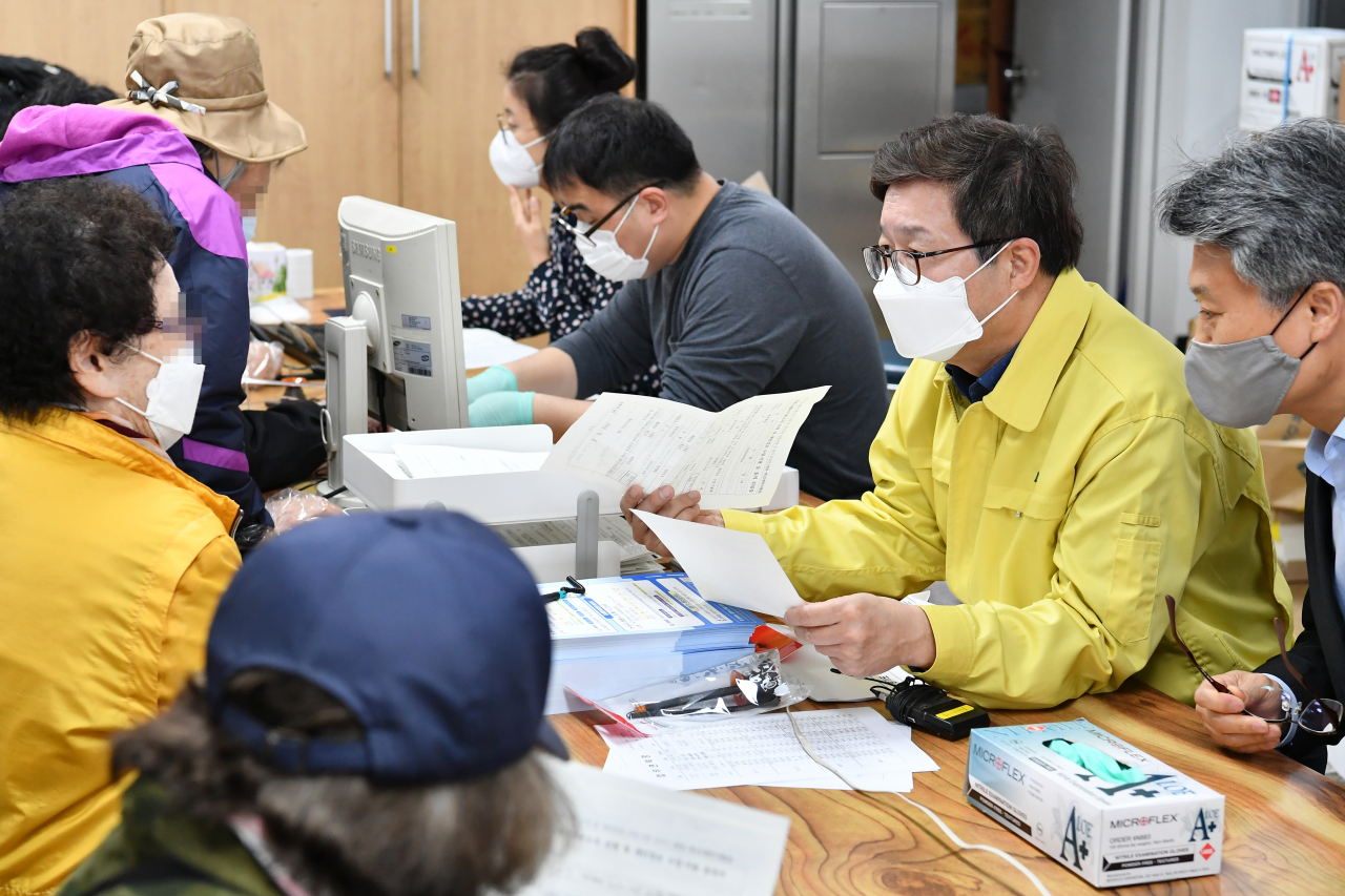 염태영 시장(오른쪽)이 권선1동행정복지센터에서 재난기본소득을 신청하는 시민에게 방법을 안내하고 있다. [수원시 제공]