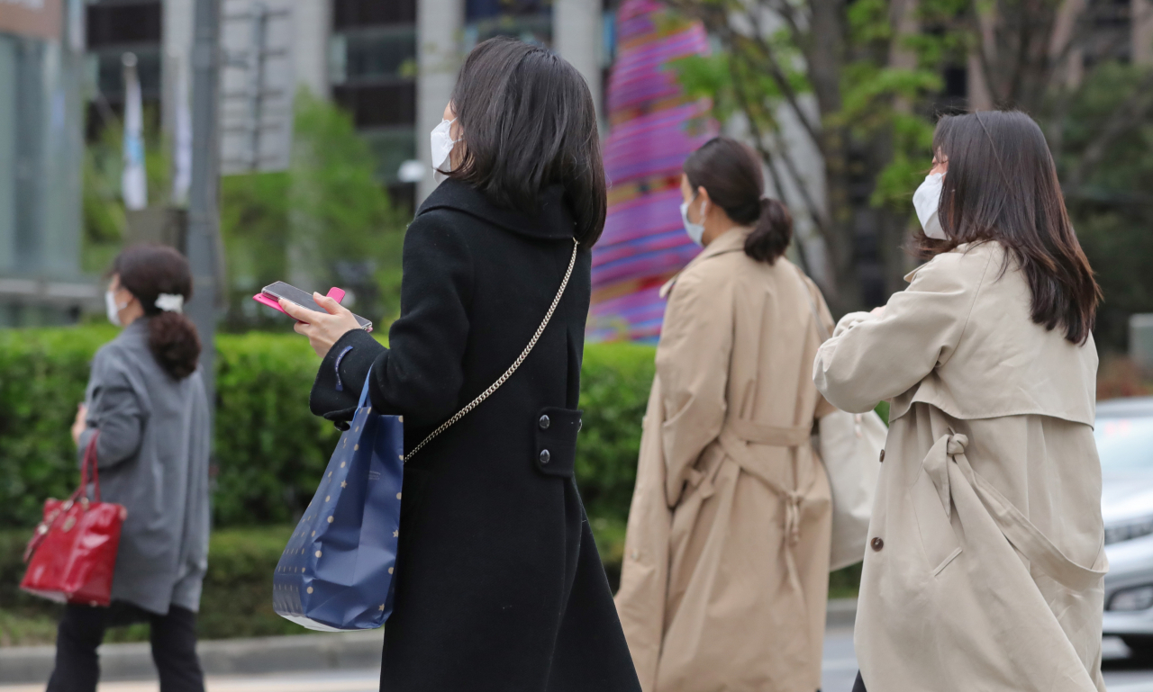 서울 최저 기온이 10도로 떨어진 지난 20일 오전 서울 종로구 광화문광장에서 시민들이 발걸음을 재촉하고 있다. 겨울에 입을 법한 코트를 다시 꺼내 입은 시민도 눈에 띈다. [연합]