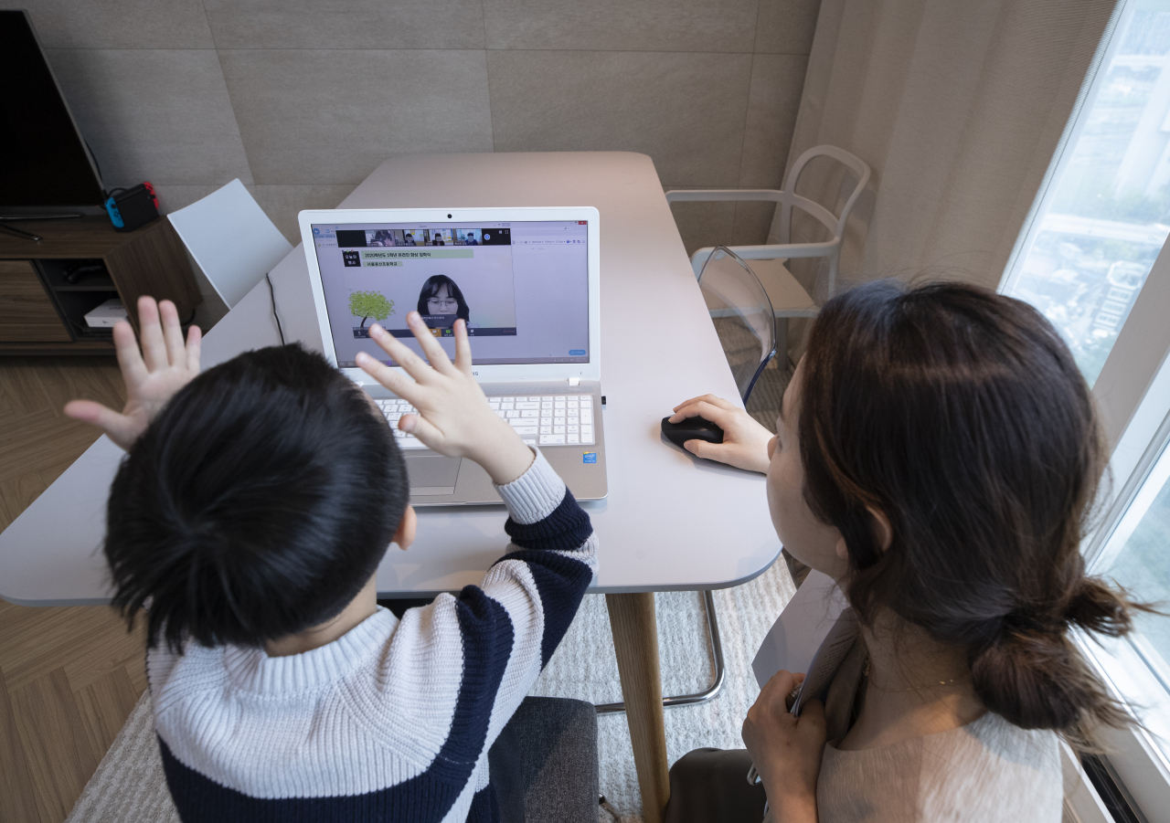 지난 20일 오전 서울 용산구의 한 가정에서 용산초등학교 1학년에 입학한 신입생 어린이가 엄마와 함께 노트북 화면을 통해 온라인 입학식을 갖고 있다. [연합]