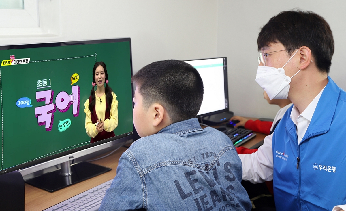 우리금융그룹 자원봉사단원이 그룹홈 아동과 함께 그룹홈 공부방에서 온라인 수업을 듣고 있다. [우리금융 제공]