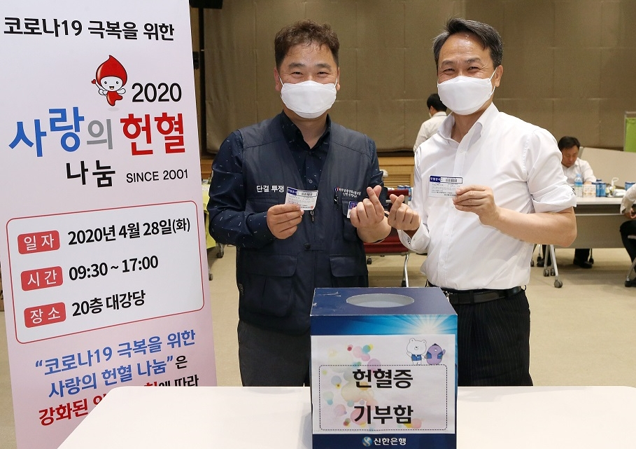 서울 중구 신한은행 본점에서 진행된 코로나19 극복을 위한 사랑의 헌혈 나눔 캠페인에서 진옥동 은행장(오른쪽)과 김진홍 노조위원장이 헌혈 후 헌혈증을 기부하고 있다. [신한은행 제공]