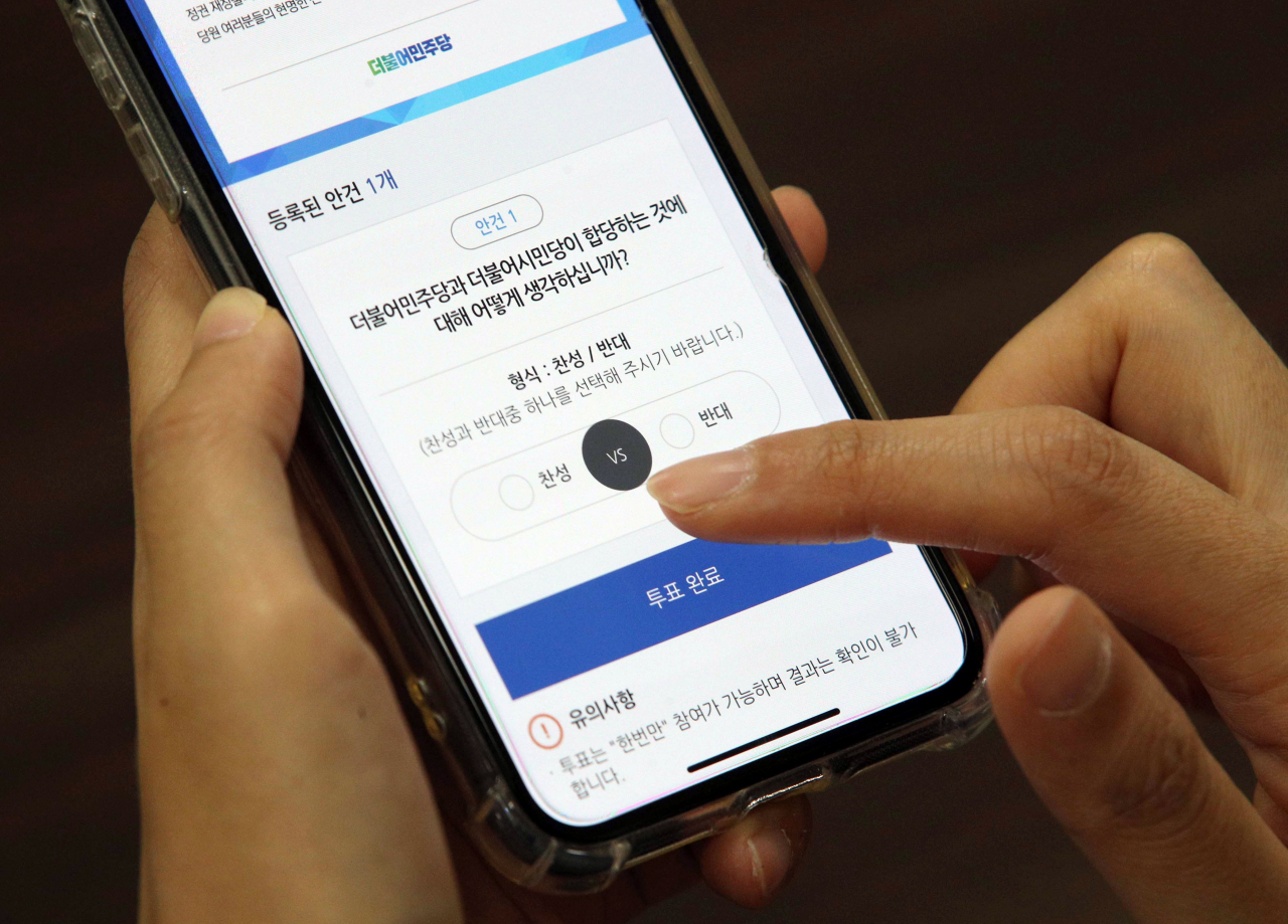 7일 오전 국회에서 한 더불어민주당 당원이 스마트폰으로 더불어민주당-더불어시민당 합당 여부를 묻는 권리당원 투표를 하고 있다. [연합]