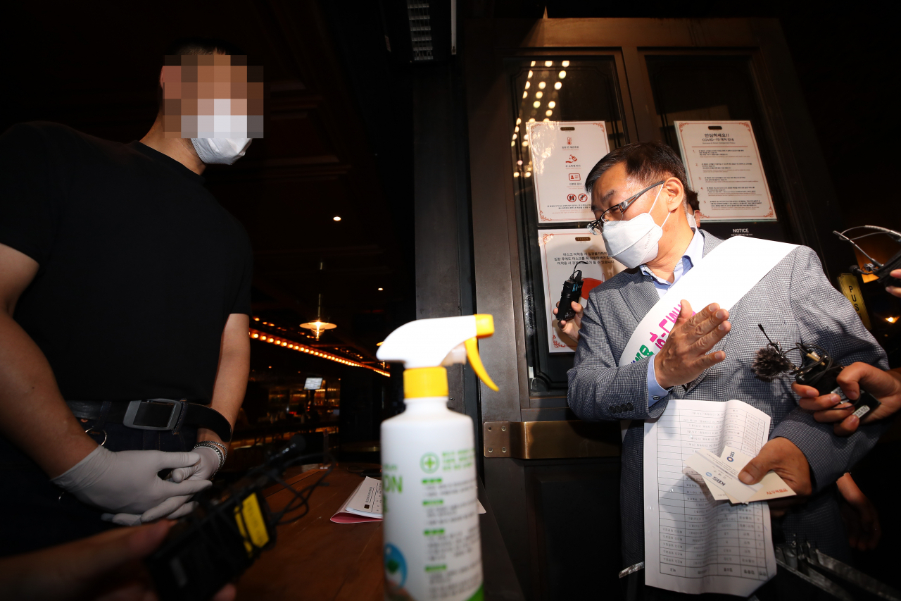 경기도 용인 66번 환자가 다녀간 서울 이태원 클럽에서 신종 코로나바이러스 감염증(코로나19) 추가 감염이 잇따르자 정부가 클럽 등 유흥시설을 대상으로 한 달 동안 운영 자제를 권고하는 행정명령을 내린 8일 오후 서울 이태원의 펍에서 용산구청 관계자가 준수사항을 설명하고 있다. 연합뉴스