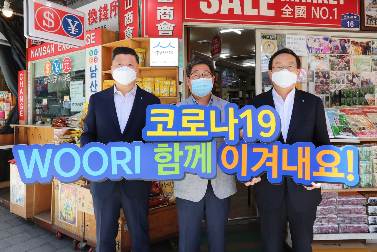 8일 손태승 우리금융그룹 회장(사진 오른쪽)과 권광석 우리은행장(사진 왼쪽)이 박칠복 남대문시장 남산상회 대표와 코로나19 극복을 다짐하며 기념촬영을 하고 있다. [우리금융 제공]