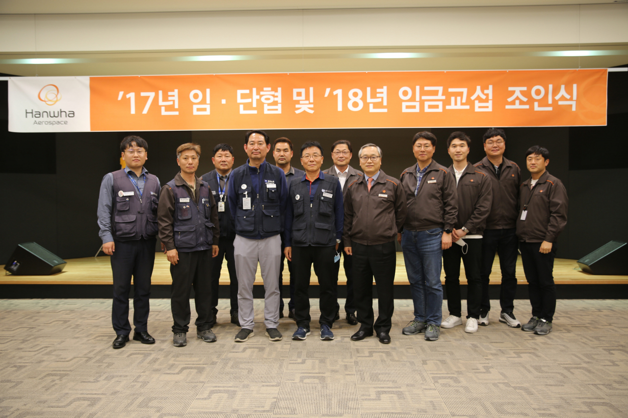 한화에어로스페이스 신현우 대표(사진 앞줄 왼쪽에서 다섯번째), 윤종균 금속노조 지회장(사진 앞줄 왼쪽에서 세번째)와 강웅표 금속노조 경남지부 부지부장(사진 앞줄 왼쪽에서 네번째) 등 노사 대표들이 지난 8일 경상남도 창원시 한화에어로스페이스 사업장에서 열린 ‘2017년 2018년 임단협 조인식’ 직후 기념촬영을 하고 있다. [한화에어로스페이스 제공]