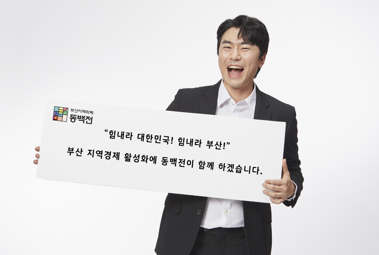 동백전 홍보모델인 배우 이시언이 부산 시민들을 응원하는 플래카드를 들고 있다. [KT 제공]