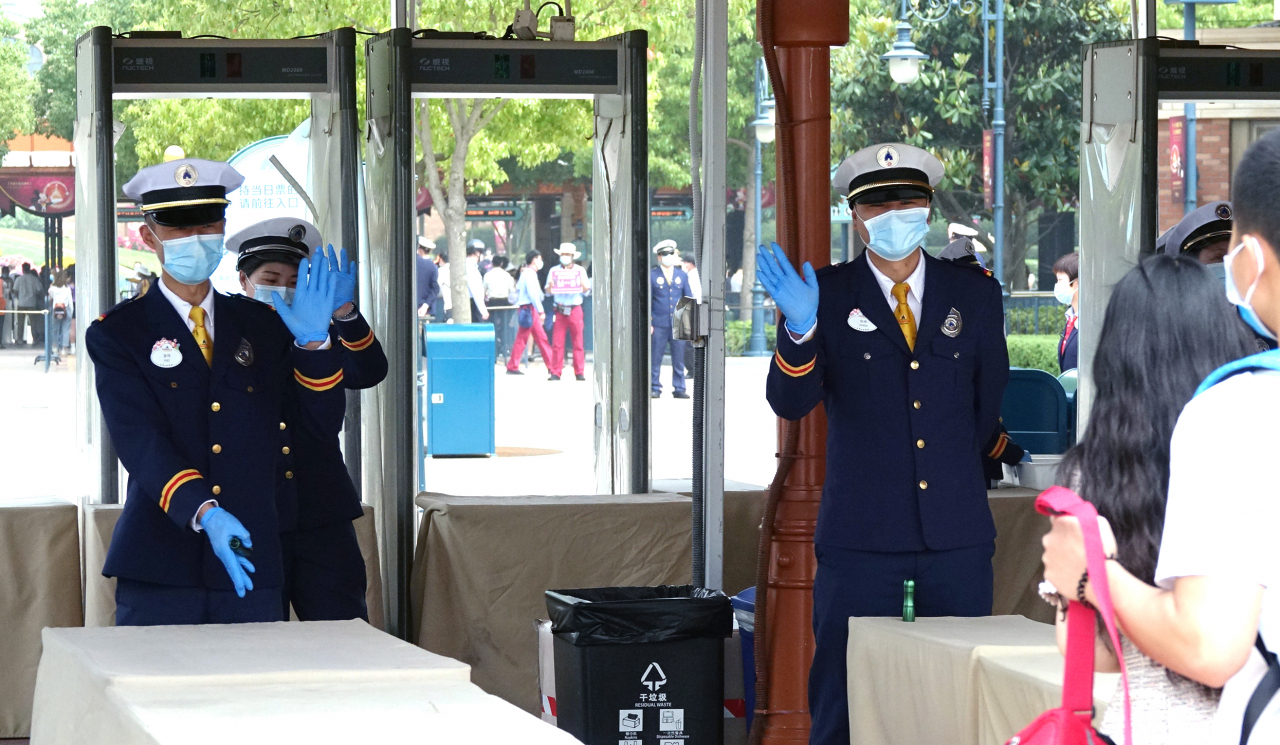 11일 중국 상하이 디즈니랜드에서 직원들이 입장하는 관람객에게 손을 들어 인사하고 있다. 상하이 디즈니랜드는 신종 코로나바이러스 감염증으로 문을 닫은 지 석 달여 만에 이날 다시 문을 열었다. [연합]