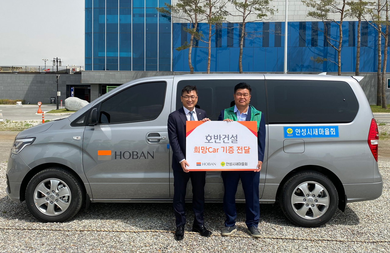 손달원 호반건설 상무(왼쪽)가 12일 경기 안성시 현수동에서 김진원 안성시새마을회장에게 45번째 희망카 전달식을 가진 뒤 기념사진을 찍고 있다. [호반건설 제공]