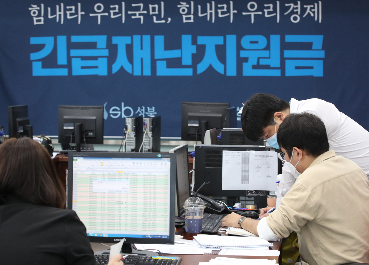 12일 서울 성북구청에서 직원들이 긴급재난지원금 신청과 관련해 안내, 상담을 하고 있다.[연합]