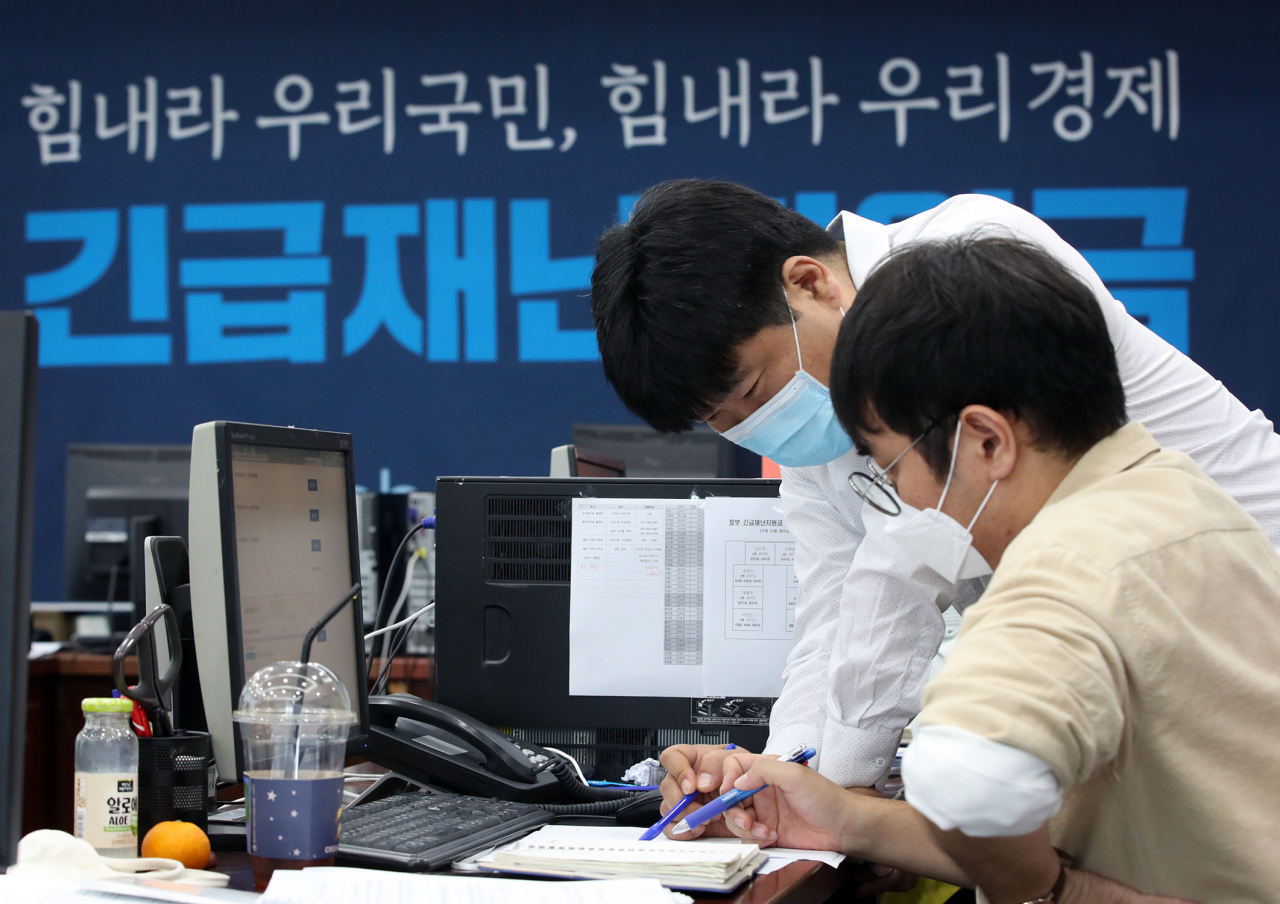 12일 서울 성북구청에서 직원들이 긴급재난지원금 신청과 관련해 안내, 상담을 하고 있다. [연합]
