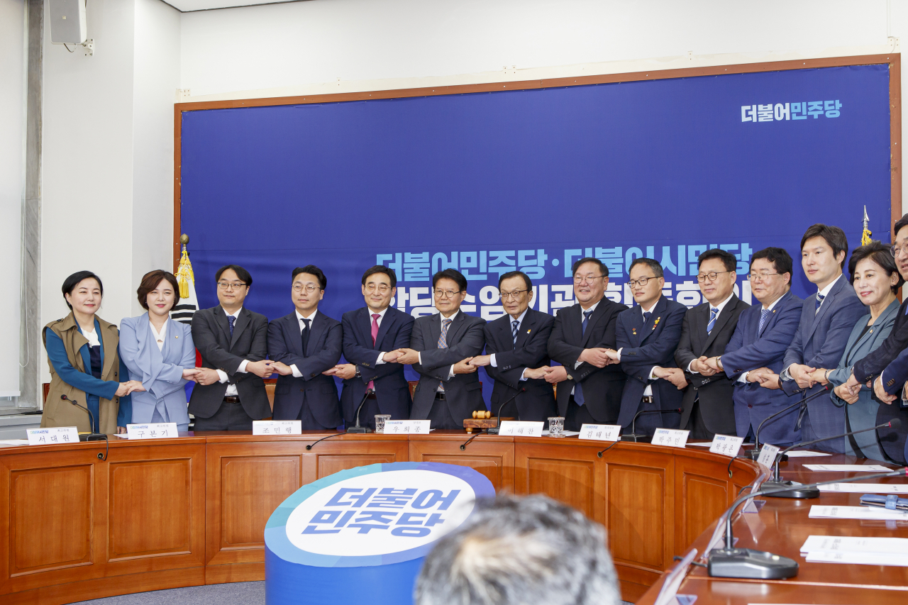 더불어민주당 지도부와 더불어시민당 지도부가 13일 국회에서 열린 합당수임기관 합동회의에서 손을 잡고 있다.[민주당 제공]
