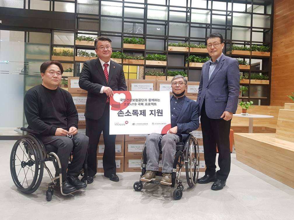 국민건강보험공단 관계자가 지난 12일 한국장애인단체총연맹과 한국장애인단체총연합회에 코로나19 예방물품 손소독제 2600개를 전달한 후 기념사진을 찍고 있다. [건강보험공단 제공]