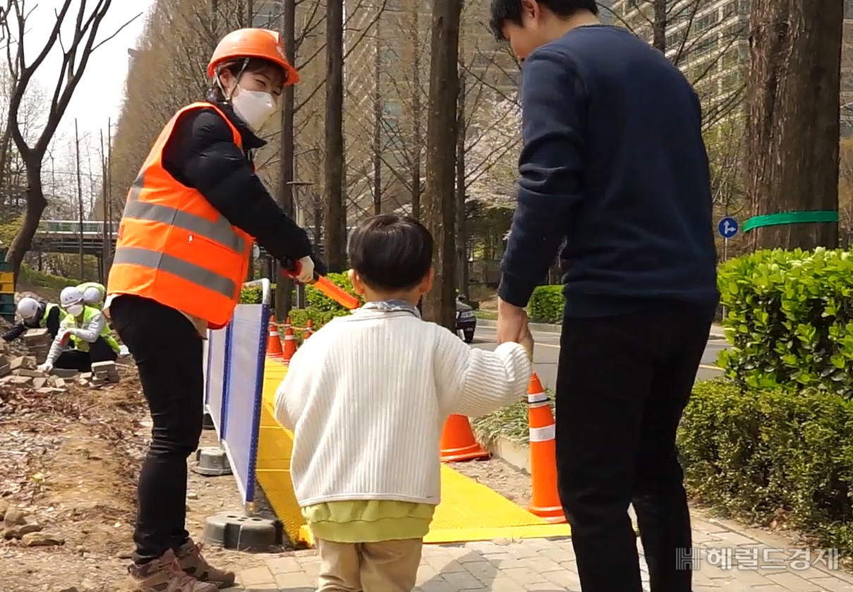 보행안전도우미가 유아를 동반한 시민에게 공사장 임시통행로를 안내하고 있다. [서울시설공단]