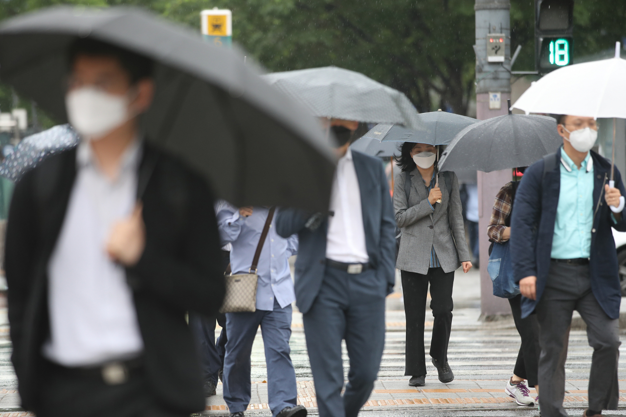 비가 내리는 15일 오전 서울 종로구 세종대로네거리에서 우산을 쓴 시민들이 발걸음을 재촉하고 있다. 신종 코로나바이러스 감염증(코로나19) 탓에 모든 시민이 마스크를 쓰고 있다. [연합]