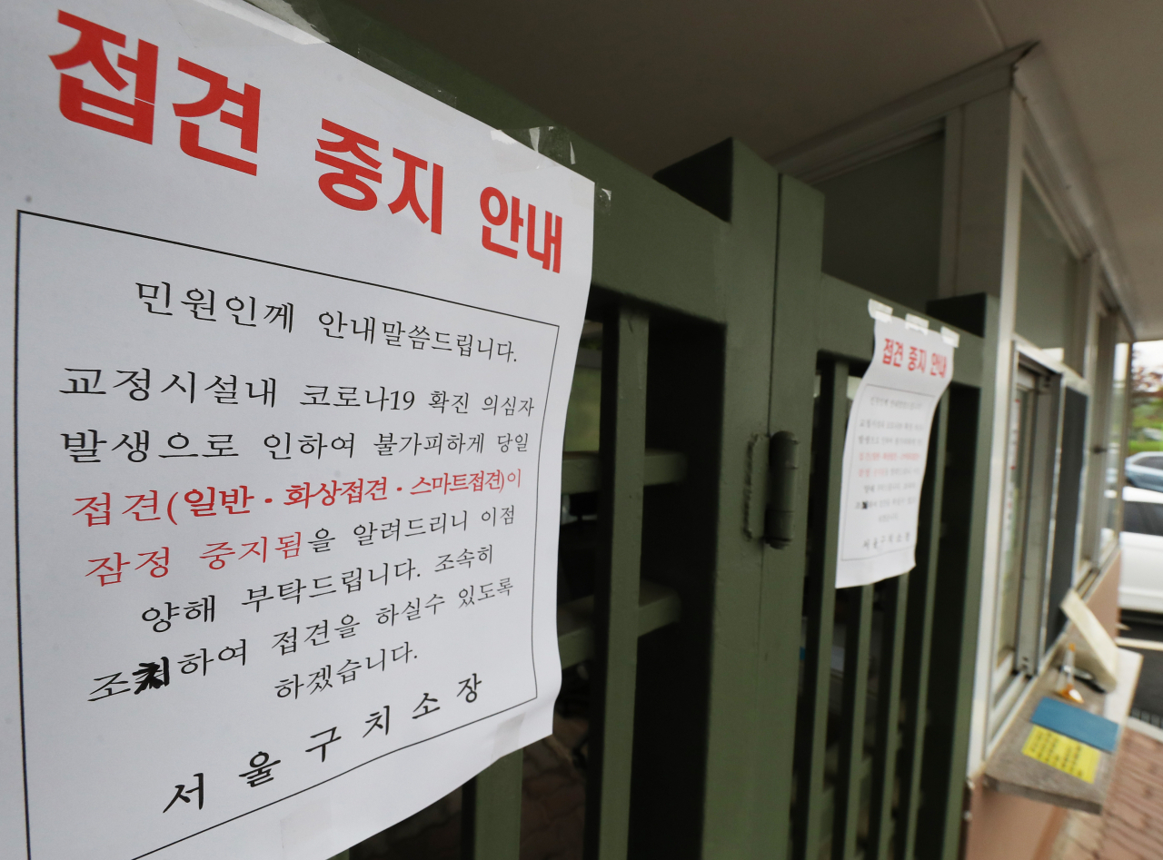 교도관이 신종 코로나바이러스 감염증(코로나19) 확진 판정을 받은 경기도 의왕시 서울구치소에 15일 오후 접견 중지 안내문이 붙어 있다. 서울구치소는 외부인과의 접촉을 최소화하기 위해 전날부터 일반 및 공무상 접견을 일시 중지했다. 또 대한변호사협회와 협의해 변호인 접견도 일시 중지했다.[연합]