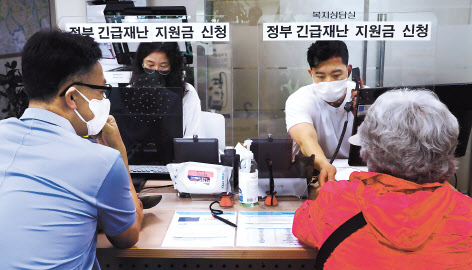 코로나19 대응을 위한 긴급재난지원금 오프라인 신청 첫날인 18일 오전 서울 용산구 용문동 주민센터 직원들이 시민들의 신청서 접수를 받고 있다. 박해묵 기자