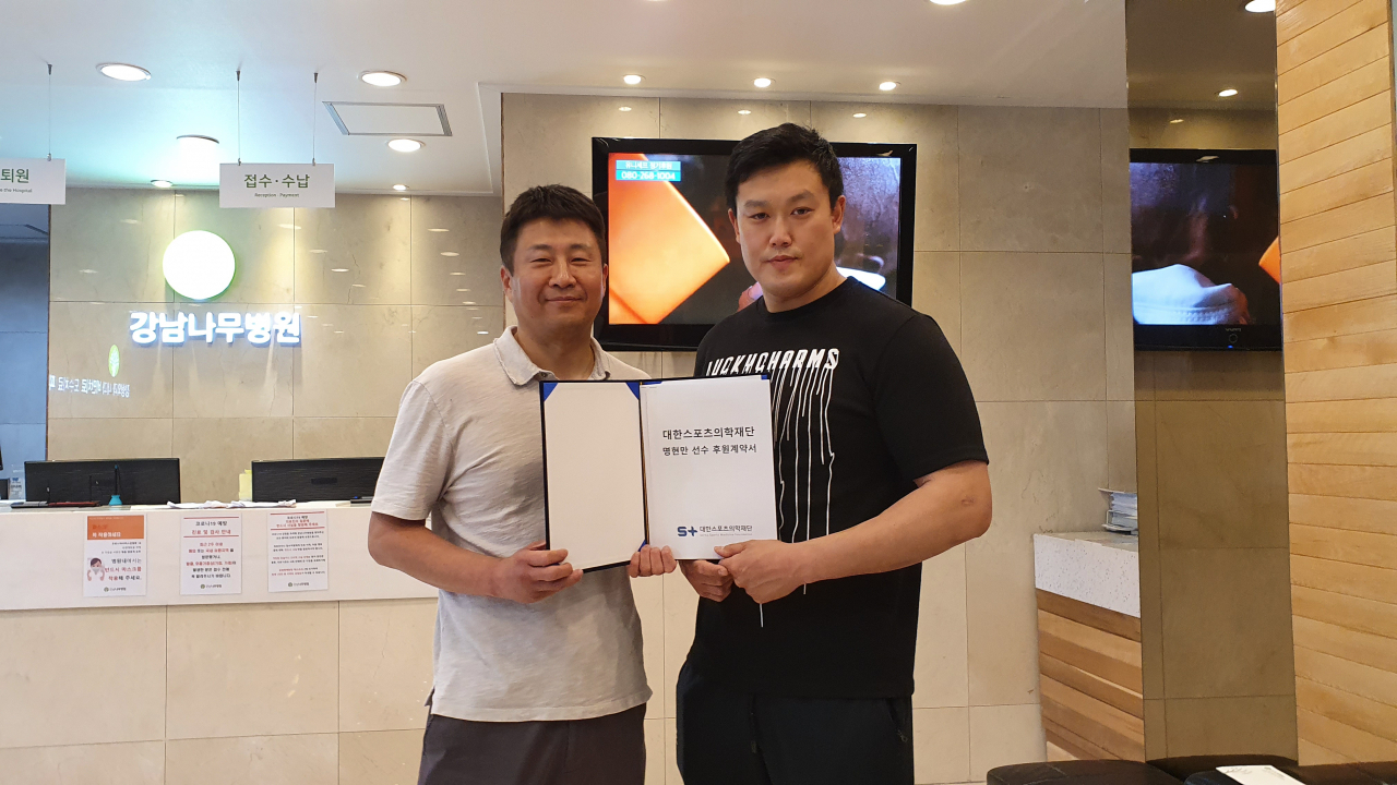 이성찬(왼쪽) 대한스포츠의학재단 이사장과 파이터 명현만이 밝은 표정으로 후원협약서를 들어보이고 있다.