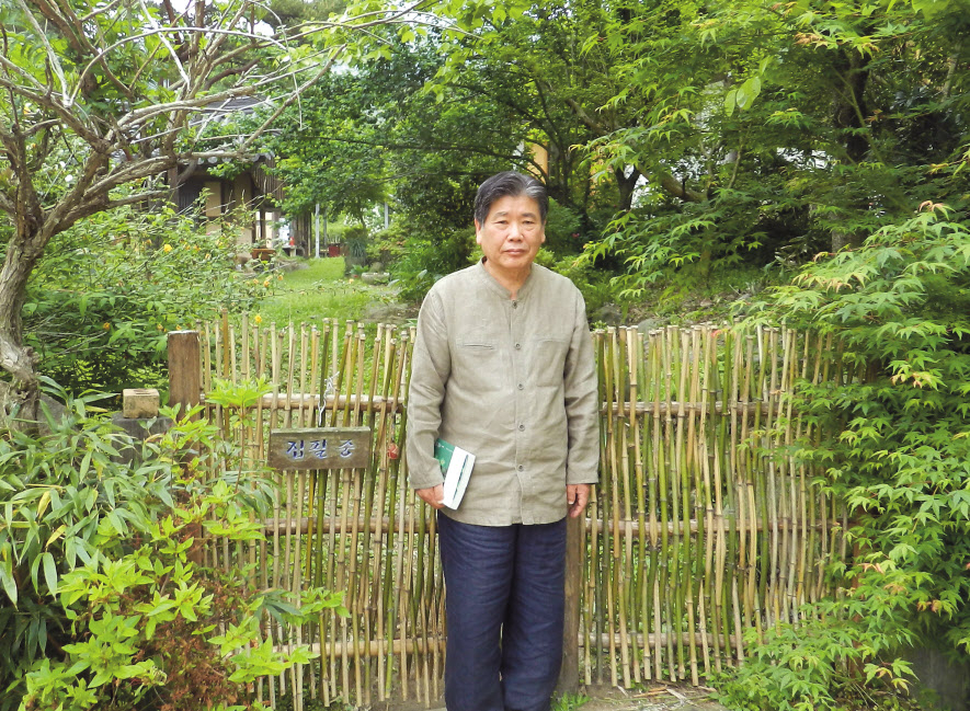 18일 만난 정찬주 작가가 자신의 거처인 전남 화순군 이양면 ‘이불재’글방의 정문 앞에서 책을 들고 서 있는 모습. 나무를 엮어 토속적인 느낌을 물씬 풍기는 낮은 문에 ‘집필중’이란 팻말이 붙어 있다. 박대성 기자