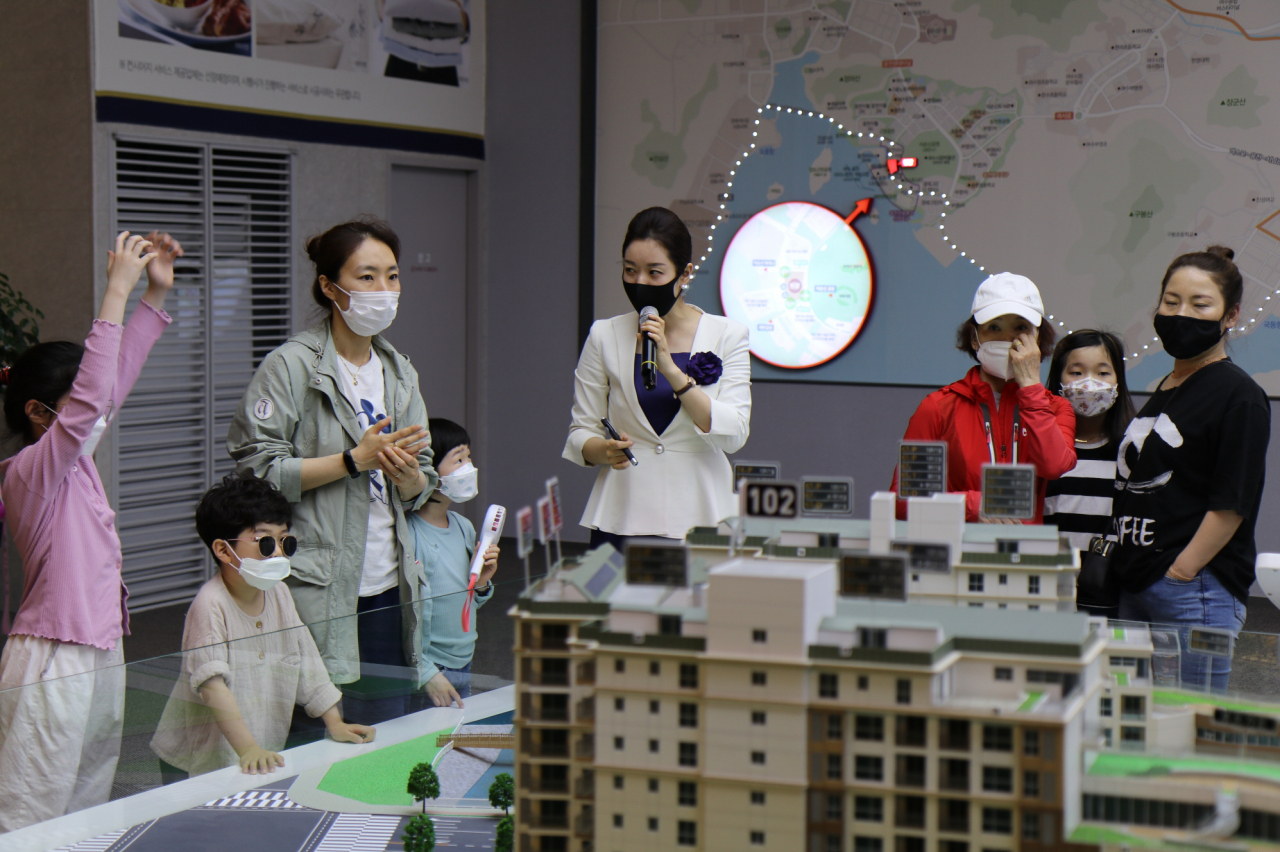 지난 15일 문을 연 '웅천 트리마제 벨마레' 홍보관을 찾은 방문객이 단지 모형을 보며 설명을 듣고 있다.