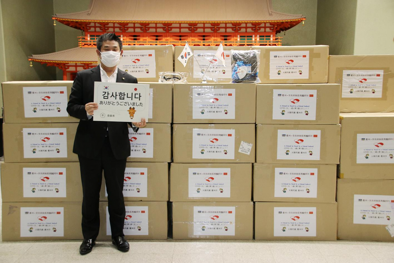 경주시가 지난 17일 자매결연 도시인 일본 나라시와 교류도시인 교토시에 각각 비축 방호복 1200세트와 방호용 안경 1000개씩을 항공편으로 보냈다고 21일 밝혔다. 사진은 일본 나카가와 겐 나라시장이 경북 경주시가 보낸 방역물품을 받은 후 '감사합니다'란 팻말을 들고 서 있는 모습. [연합]