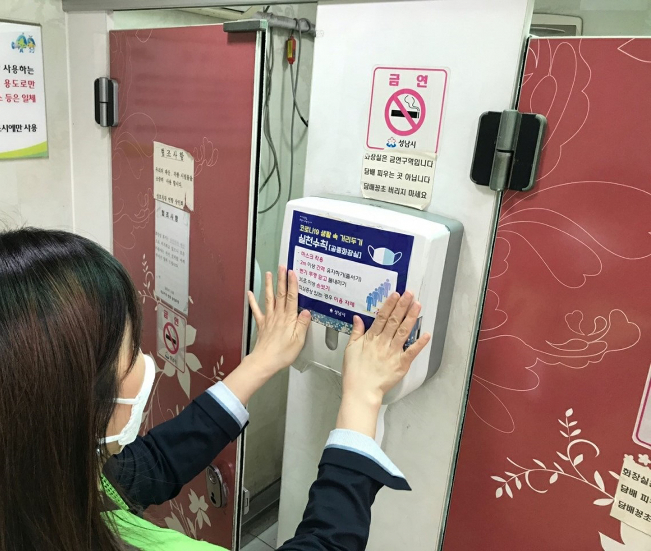 성남시 공무원이 공중화장실에 생활속 거리두기 점검을 나가 안내문을 붙이고 있다. [성남시 제공]