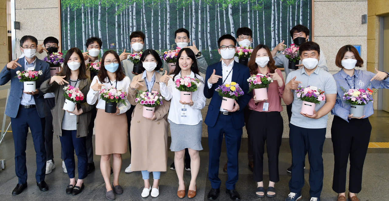국민연금공단 본부 직원들이 26일 화훼농가의 어려움을 돕기 위해 구매한 생화를 들고 기념 촬영을 하고 있다. [국민연금공단 제공]