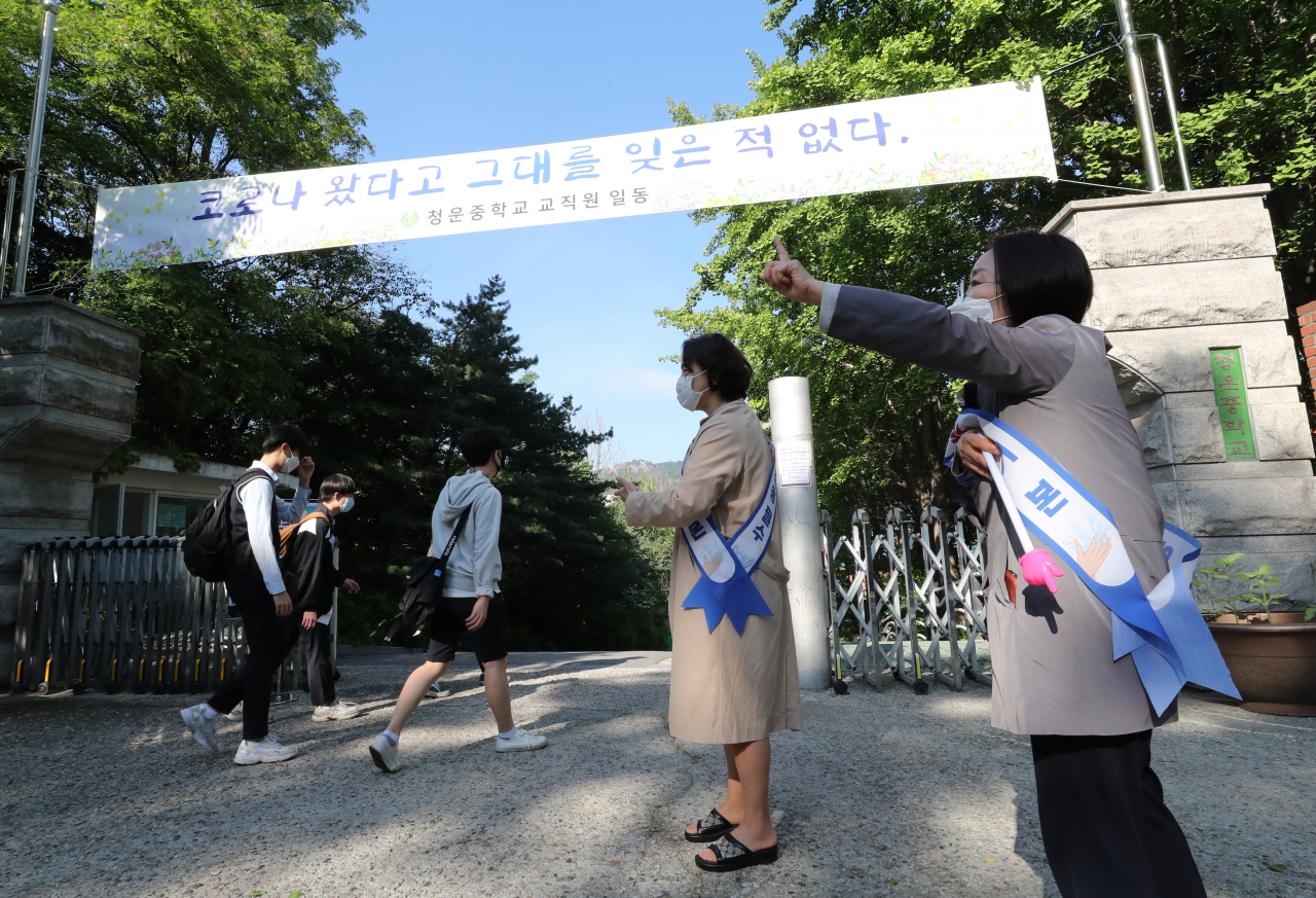 중학교 3학년 등교 수업이 시작된 27일 오전 서울 종로구 청운중학교에서 선생님들이 등교하는 학생들을 향해 간격 유지를 지도하고 있다. 연합뉴스