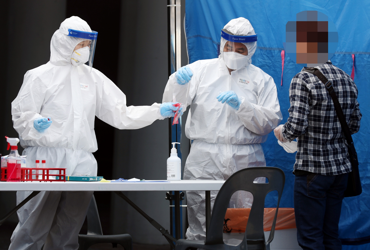 경기도 부천 쿠팡 물류센터에서 신종 코로나바이러스 감염증(코로나19) 확진자가 속출한 27일 오전 경기도 부천시 종합운동장 외부 주차장에 마련된 선별진료소에서 보건 당국 관계자들이 한 시민을 검체 검사하고 있다. 연합뉴스