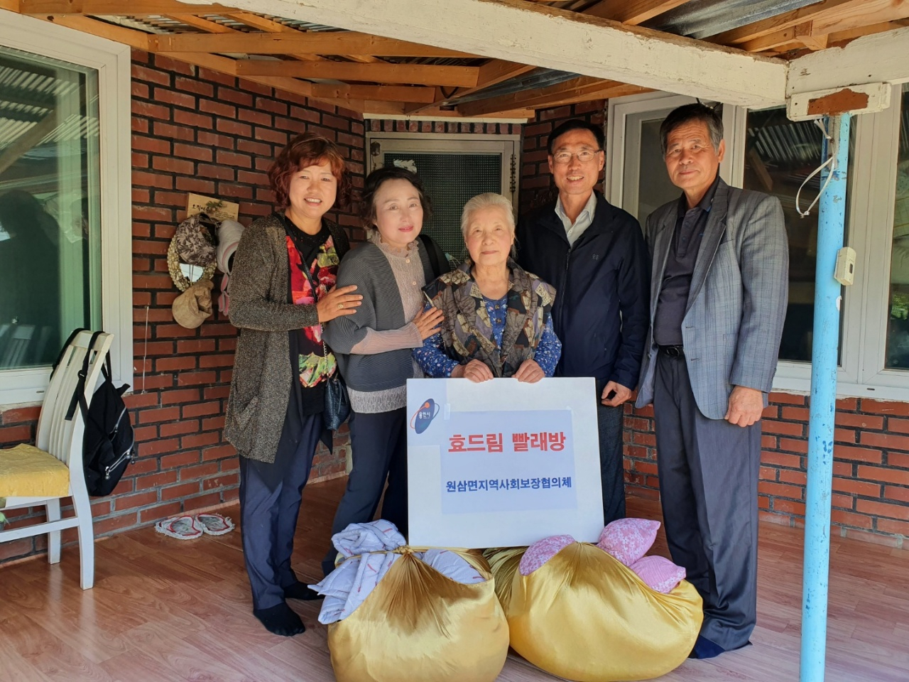 협의체 위원들이 노인에게 빨래를 전달하고 기념촬영을 하고있다. [용인시 제공]