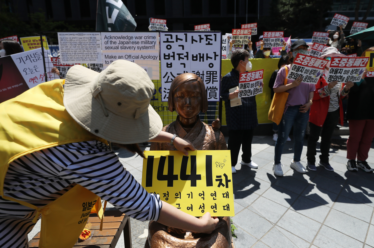 지난 27일 서울 종로구 옛 일본대사관 앞에서 열린 제1441차 일본군 위안부 피해자 문제 해결을 위한 정기 수요시위에서 한 관계자가 일본군성노예제문제해결을위한정의기억연대(정의연) 주최를 알리는 팻말을 소녀상 앞에 두고 있다. [연합]