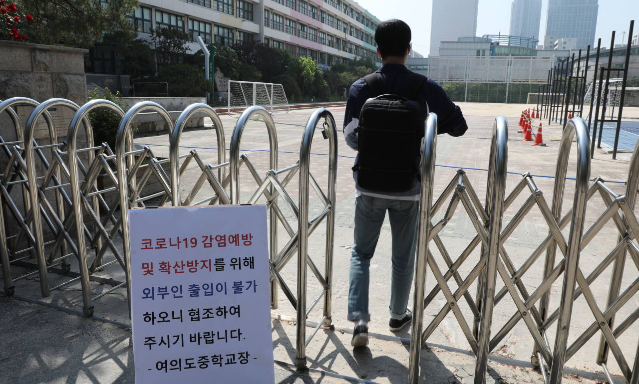 29일 오전 서울 여의도중학교에서 관계자가 학교 정문으로 들어가고 있다. 이 학교는 여의도 학원강사와 수강생 코로나19 확진으로 이날 예정된 학생 등교를 온라인 수업으로 변경했다. [연합]