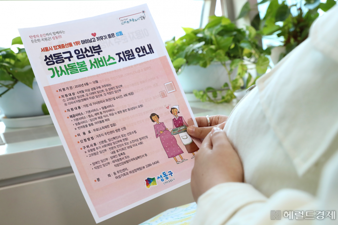 한 임신부가 성동구 임신부 가사돌봄서비스 지원 안내 책자를 들고 있다. [성동구]