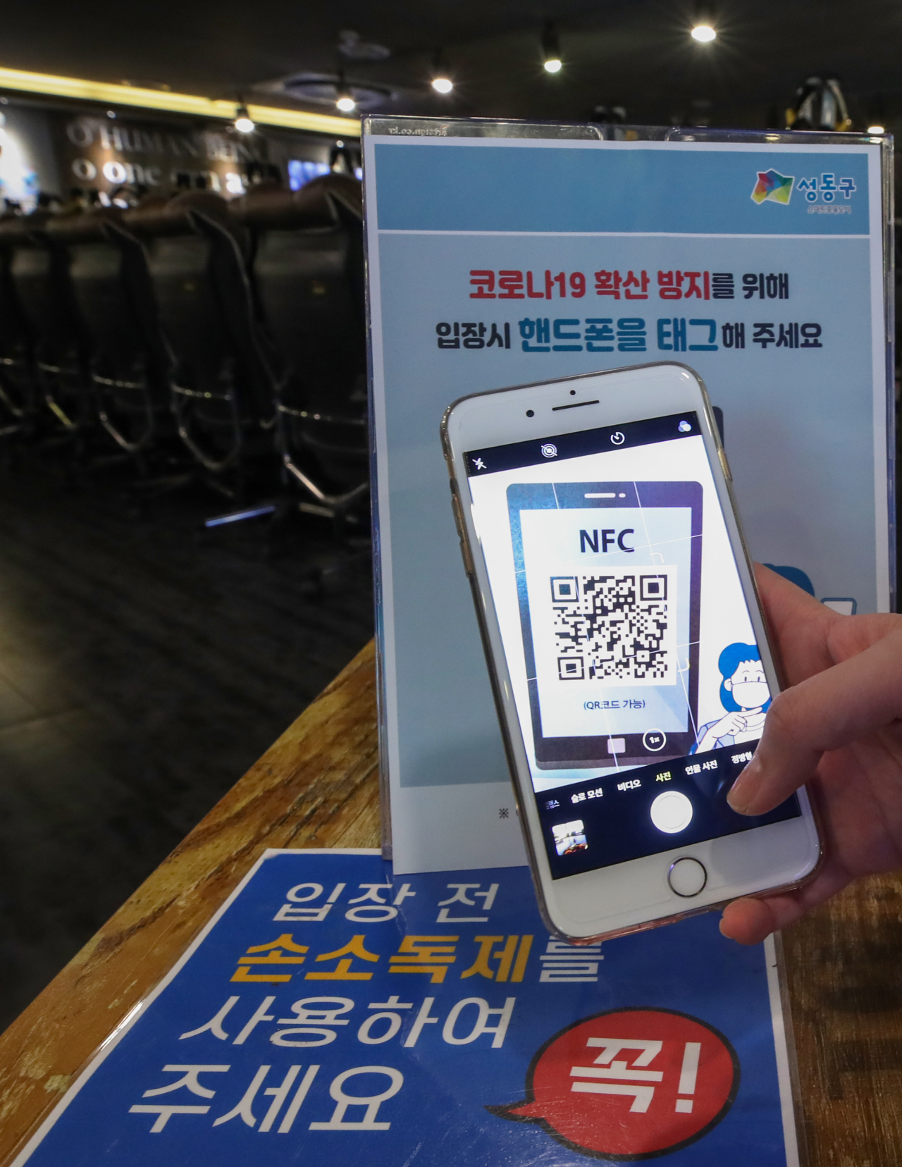 1일 서울 성동구의 한 PC방에서 직원이 입구에 비치된 QR코드를 스캔해 방문자의 모바일 전자 명부 작성 과정을 시연하고 있다. 중앙재난안전대책본부 따르면 이날부터 7일까지 1주일간 서울·인천·대전지역의 19개 시설에서 QR코드를 이용한 전자출입명부 시스템이 시범 운영된다. QR코드를 이용한 전자출입 명부 시스템은 클럽과 노래방 등 고위험시설뿐만 아니라 성당, 교회, 도서관, 영화관, 일반음식점, 병원 등 상당수의 다중이용시설에서도 도입될 예정이다. 서울 성동구는 중대본 발표에 앞서 지난달 15일부터 관내 PC방·노래방 등 다중이용시설에서 출입자가 업소를 방문할 때 NFC 태그 또는 QR코드 스캔으로 본인 인증이 가능하도록 '모바일 전자명부' 시스템을 별도 운영하고 있다. [연합]