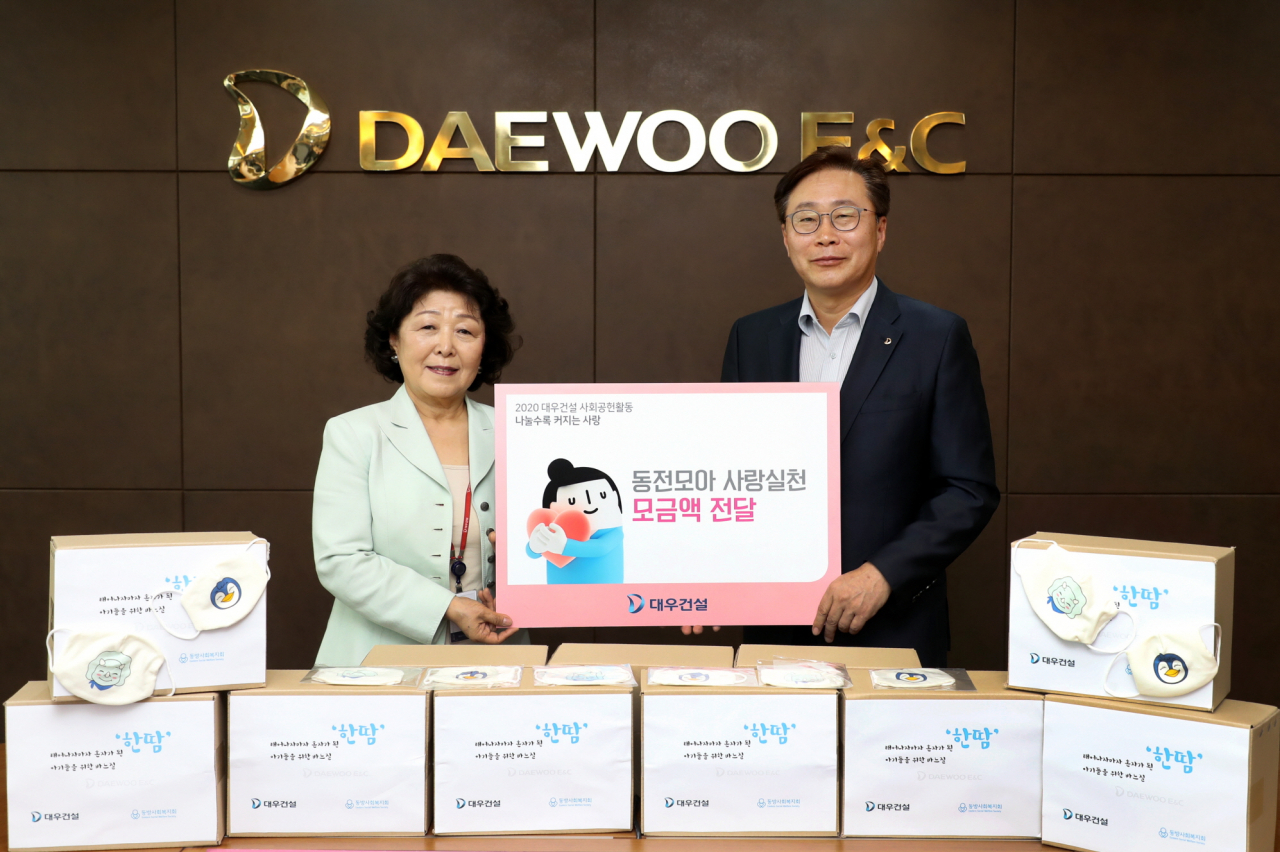 대우건설은 지난달 26일 서울 을지로 본사에서 동방사회복지회에 임직원과 가족이 참여해 만든 마스크와 후원금을 전달했다. 사진은 전달식에 참여한 조인환(오른쪽) 대우건설 인사관리지원본부장과 김진숙 동방사회복지회 회장의 모습 [대우건설 제공]