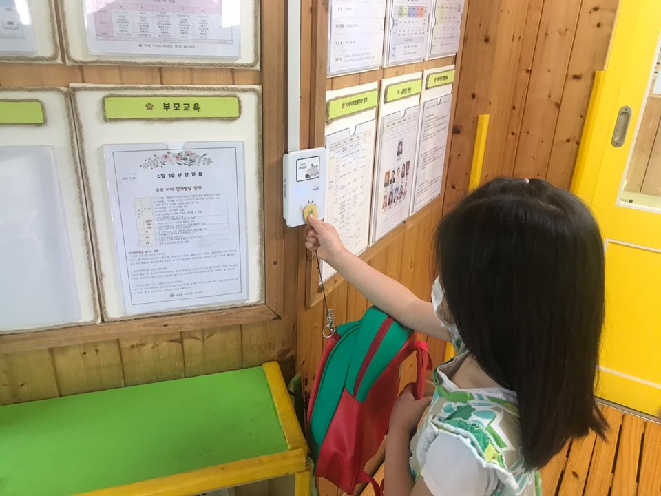 지역 내 어린이집에서 자동전자출결시스템 리더기에 태그를 대고 있는 아동의 모습. [광진구 제공]