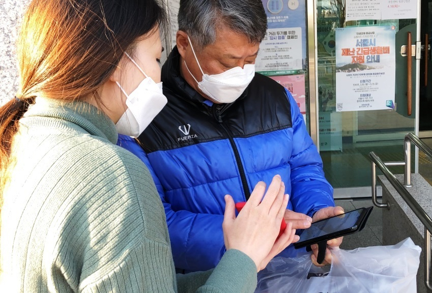 시립 용산노인복지관 관계자가 돌봄 서비스 대상자에게 스마트폰으로 유튜브 동영상을 보는 법을 알려주고 있다. [용산구]