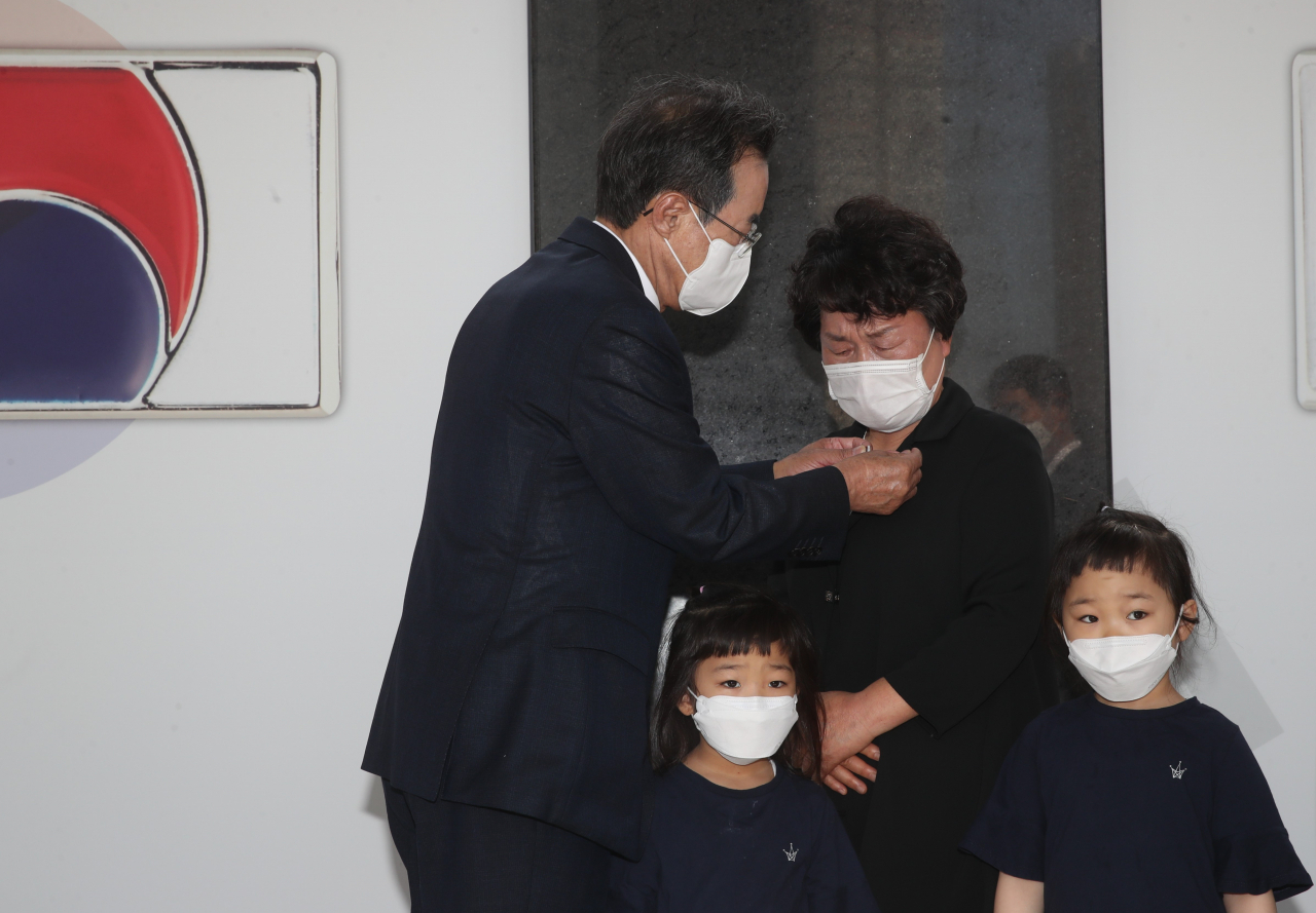 이성희 농협중앙회장(오른쪽)이 6.25전쟁 참전용사 유족대표에게 태극기 배지를 달아주고 있다. [농협 제공]