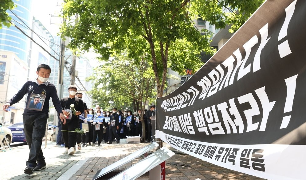 이천 물류창고 화재 유가족들이 지난달 29일 오후 서울 서초구 한익스프레스 본사 앞에서 시행사·시공사 등이 적힌 팻말에 국화를 던지는 퍼포먼스를 하고 있다. [연합]